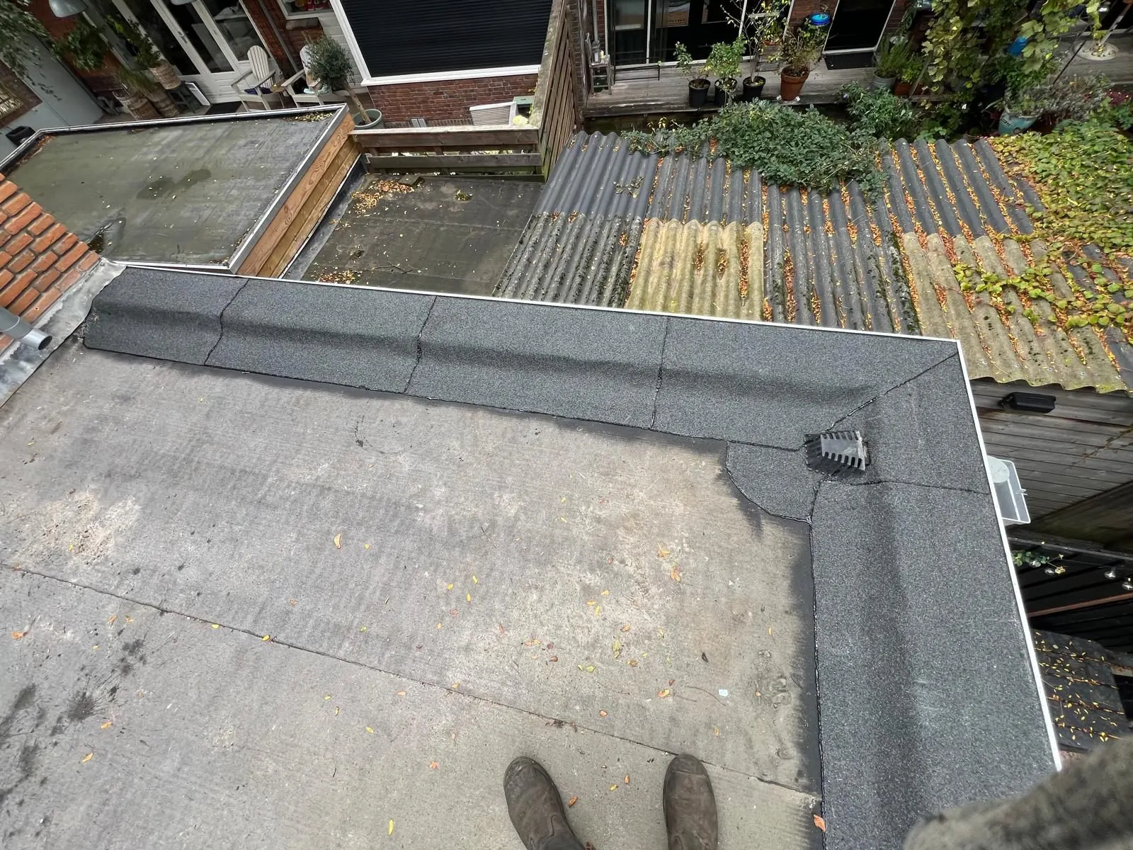 Dakdekker inspecteert een oud bitumen plat dak op scheuren en blazen