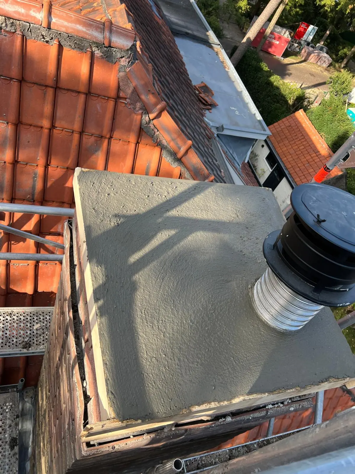 Schoorsteen met nieuwe betonnen afdekplaat op een pannendak