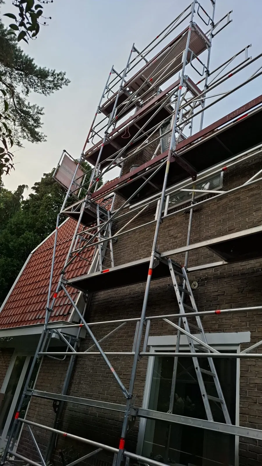Steiger tegen een woning met pannendak voor herstel na stormschade